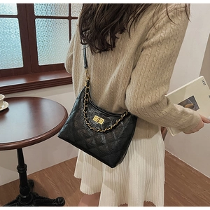 Borsa a spalla in pelle nera trapuntata con catena dorata indossata da modella in interni