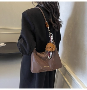 Vista de cerca del bolso hobo de cuero marrón brillante con cuentas de ámbar y osito