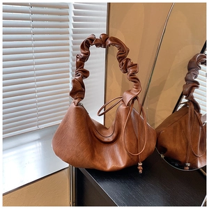 Détail de sac en cuir marron vintage avec bandoulière plissée et finitions à cordon de serrage