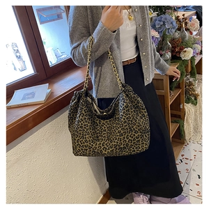 Detail of leopard print tote bag with golden metal chain straps and canvas texture