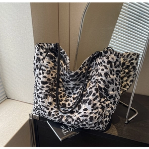 Detail of leopard print quilted tote bag with diamond stitching and black shoulder straps