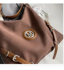 Dettaglio della borsa tote marrone scuro con logo M argento e tracolla in pelle regolabile