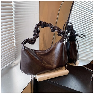 Détail du sac hobo en cuir marron foncé avec poignée plissée sur un décor élégant