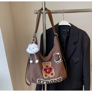 Detail of coffee brown tote with teddy bear patch, embroidery and cloud charm accessory