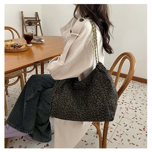 Detail of leopard print tote bag with gold chain strap and drawstring closure design