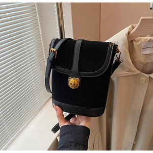 Macro shot of black bucket bag featuring suede texture and golden metal bear logo