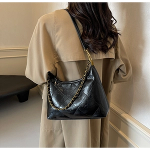 Détail du sac hobo matelassé noir avec une chaîne dorée décorative et une bandoulière en cuir