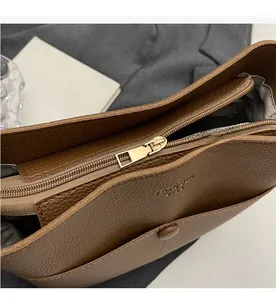 Detail view of the smooth golden metal zipper and brown lychee texture on bucket bag