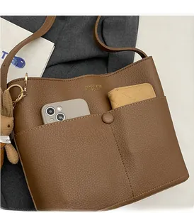 Detail of brown litchi leather tote bag showing front pocket storage and cute bunny charm