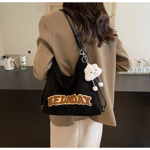 Gros plan sur un sac noir avec broderie HELNDAY et breloque en forme de nuage blanc
