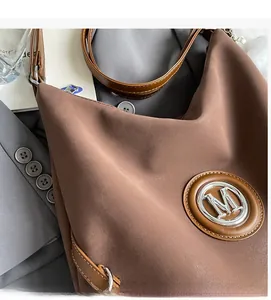 Dettaglio della borsa vintage marrone con trama opaca e logo M in metallo argento