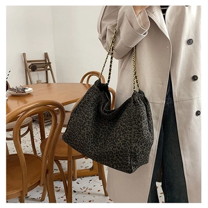 Detail of leopard print tote bag with golden metal chain straps and spacious interior