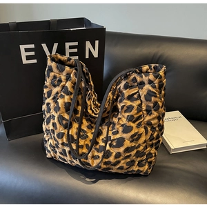 Detailed view of large leopard print quilted tote bag on a black leather sofa