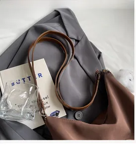 Dettaglio dei manici in pelle marrone della borsa tote su un blazer alla moda