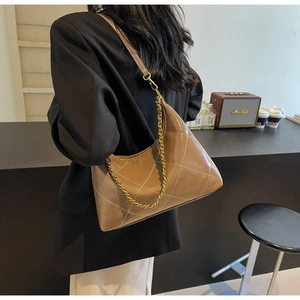 Détail du sac bandoulière matelassé en cuir verni marron avec chaîne dorée et lanière