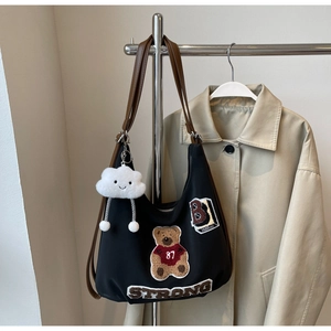 Detail of black hobo bag with teddy bear embroidery and brown leather shoulder straps