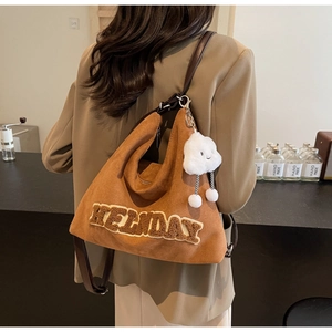 Gros plan du sac cabas en daim marron avec broderie HOLIDAY et gri-gri nuage