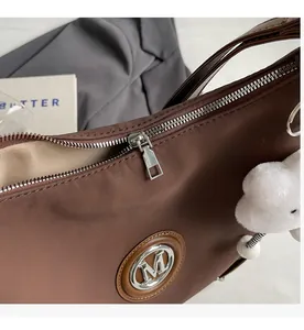 Dettaglio della cerniera argentata e del logo M su una borsa tote marrone vintage