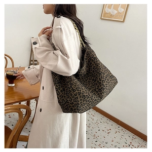 Detail of hobo tote bag featuring leopard print and gold chain strap in a cafe