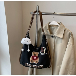 Detail of black canvas tote bag with bear embroidery and white cloud plush charm