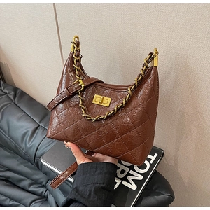 Dettaglio borsa hobo in pelle trapuntata marrone scuro con catena dorata e chiusura in metallo