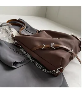 Dettaglio borsa in pelle marrone con catena argentata e tracolla regolabile
