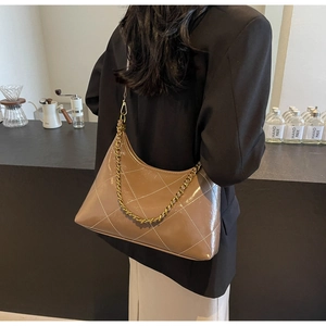 Sac en cuir marron matelassé avec chaîne dorée porté comme accessoire d'épaule chic