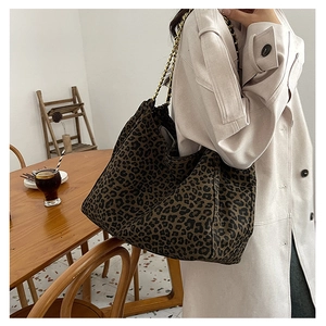 Detail view of large leopard print tote bag with golden metal chain shoulder strap