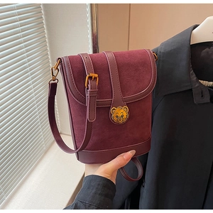 Detail of burgundy bucket bag with suede leather mix and gold bear metal clasp