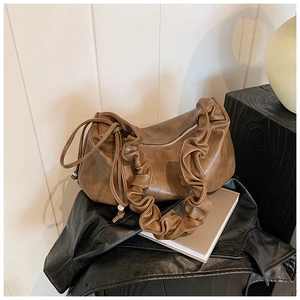 Détail d'un sac dumpling en cuir marron avec bandoulière plissée au design unique