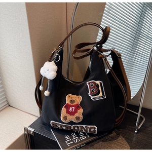 Detail of black hobo bag with teddy bear embroidery and brown leather shoulder strap