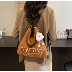 Détail du sac en daim marron avec broderie HOLIDAY et accessoire peluche nuage