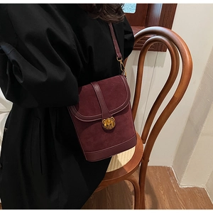 Detail of burgundy vintage crossbody bag with a gold bear buckle and suede texture