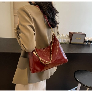 Détail du sac bandoulière matelassé rouge foncé avec chaîne dorée et cuir verni brillant
