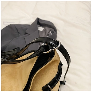 Close-up of yellow suede and black leather bag stitching with silver metal ring