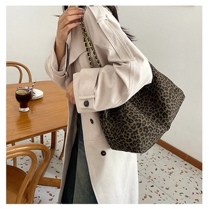 Detail of large leopard print tote bag with stylish metal chain strap in warm cafe setting