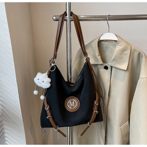 Dettaglio della borsa tote in nylon con logo M in pelle marrone e charm a nuvola bianca