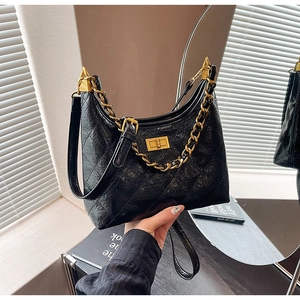 Dettaglio borsa hobo trapuntata in pelle nera cerata con catena dorata e chiusura girevole