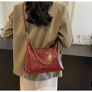 Détail du sac matelassé bordeaux avec chaîne dorée porté par un mannequin