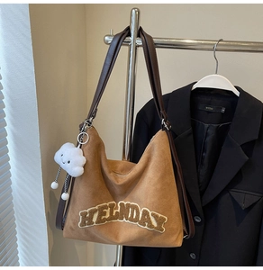 Détail du sac cabas en daim marron avec broderie HELLIDAY et breloque nuage en peluche