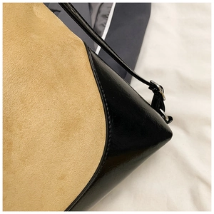 Detail of yellow faux suede and black leather patchwork bag with silver buckle