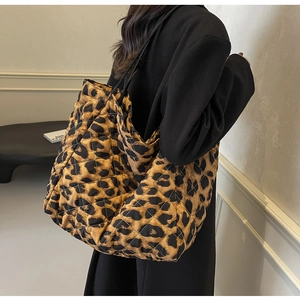 Detail of large leopard print tote bag featuring quilted diamond stitching and black straps