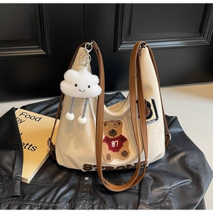 Detail of canvas hobo bag with bear embroidery, faux leather strap and cloud charm