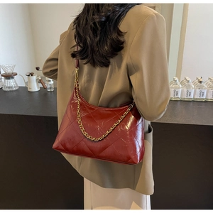 Détail du sac à bandoulière en cuir verni matelassé bordeaux avec chaîne dorée