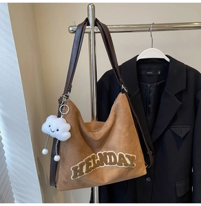 Détail du sac cabas en daim marron avec broderie HELLNDAY et breloque nuage suspendu