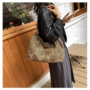 Fashionable leopard print shoulder bag with metal chain strap shown in a retro cafe setting