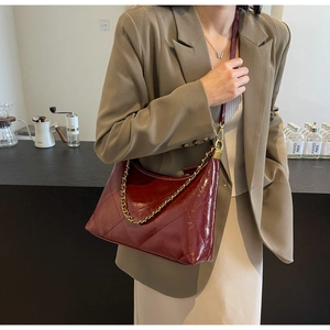 Détail du sac hobo bordeaux matelassé avec une chaîne dorée décorative élégante