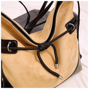 Close-up of beige suede texture and black leather stitching on large shoulder bag