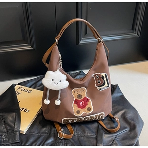 Brown nylon hobo bag featuring teddy bear embroidery and a cloud charm on a leather jacket