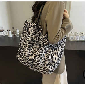 Quilted tote bag with black and white leopard print shown on shoulder in a cafe